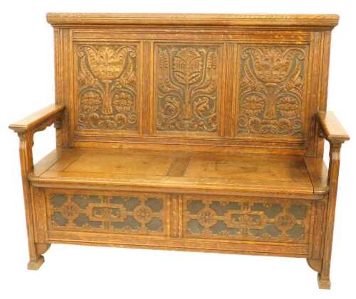 A 20thC oak settle by Lamb of Manchester, the three sectional back carved with floral motifs,...