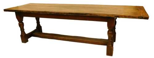 An elm refectory type table, the rectangular top raised on turned supports united by stretchers,...