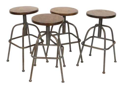 A set of four industrial steel framed rise and fall work stools, with circular seats, 63cm high...