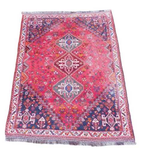 A Turkish design red ground rug, with three central guls, blue ground quadrants and multi...