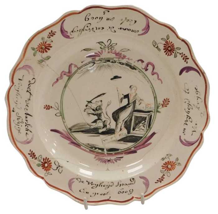 A late 18thC Leeds Creamware plate, Dutch decorated, the centre painted with a figure of Liberty...