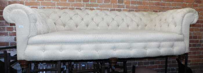 A Victorian Chesterfield style sofa, with upholstered buttoned back and arms, on turned feet...