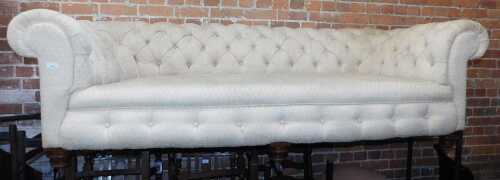 A Victorian Chesterfield style sofa, with upholstered buttoned back and arms, on turned feet...