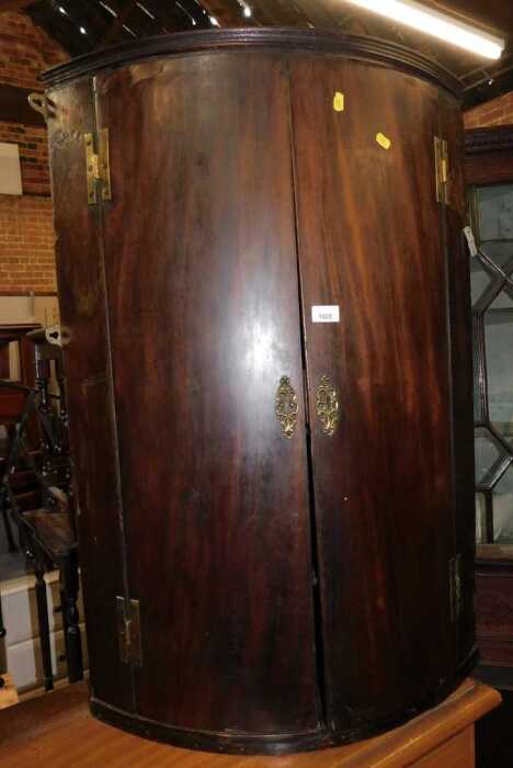 A 19thC mahogany veneered bow front hanging corner cabinet, the two doors enclosing four shelves,...