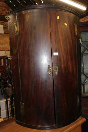 A 19thC mahogany veneered bow front hanging corner cabinet, the two doors enclosing four shelves,...
