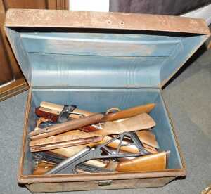 A tin trunk, containing wooden gun stocks, and others.