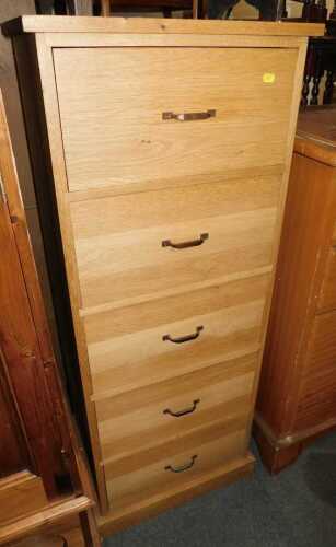 A contemporary oak five drawer narrow chest, on a plinth base, 127cm high, 51cm wide, 41cm deep.