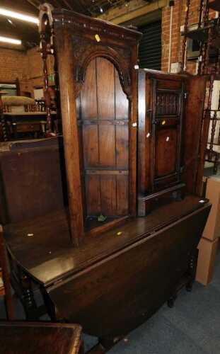 An oak oval topped drop leaf dining table, with stretcher below, together with a linen fold...