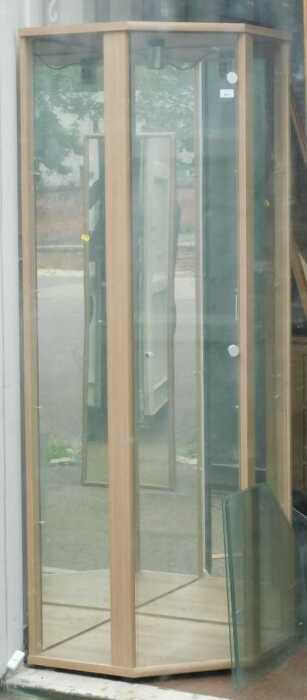 A glass corner display cabinet, with mirror back and single door.