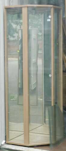 A glass corner display cabinet, with mirror back and single door.