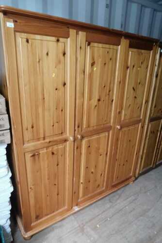 A pine three door wardrobe, opening to reveal hanging rail, raised on bun feet.