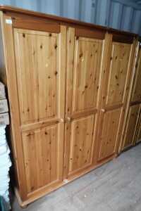 A pine three door wardrobe, opening to reveal hanging rail, raised on bun feet.