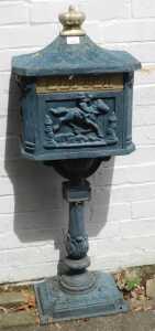 A cast iron letter box, raised on a single column above base unit.