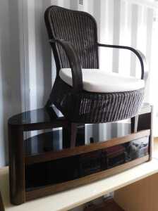 A smoked glass and veneered TV unit, and a conservatory chair, with caned back and seat. (2)