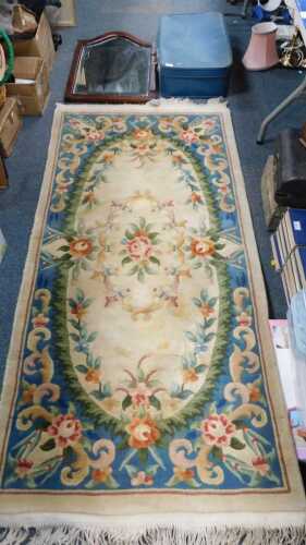 A vintage blue suitcase, a woollen machine made rug, and a bevelled mirror, with shaped arched top.