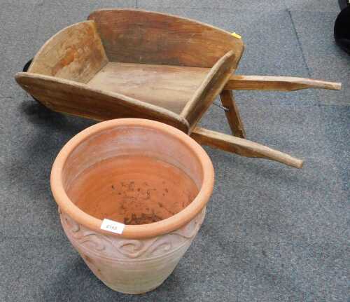 A small wooden wheelbarrow, and a large terracotta planter.