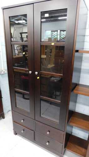 A freestanding dark wood display cabinet, with two doors above four drawers, on block feet.