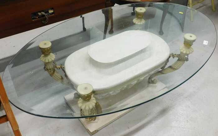 A high quality glass top coffee table, the oval top on a marble finish classical base.