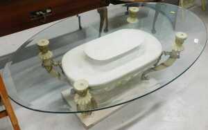 A high quality glass top coffee table, the oval top on a marble finish classical base.