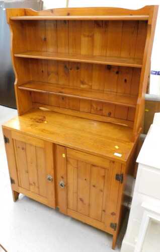 A rustic pine open dresser of small proportion, with three shelves above double cupboard, on...