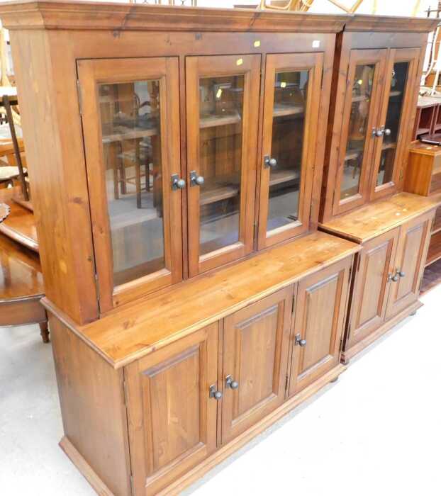 A stained pine three drawer glazed display cabinet, with triple cupboard beneath, and a similar...