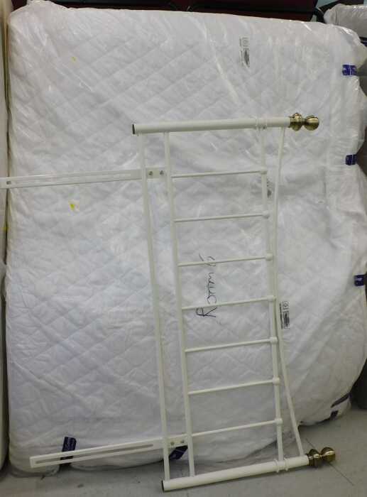 A 56" wide bed surround, comprising metal headboard with white partially wrapped mattress.