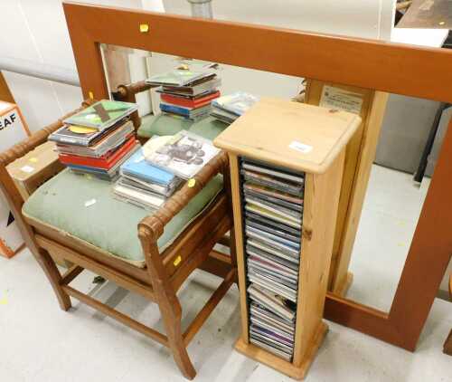 A pine CD rack, a quantity of CDs, rectangular hanging mirror, and a piano stool.