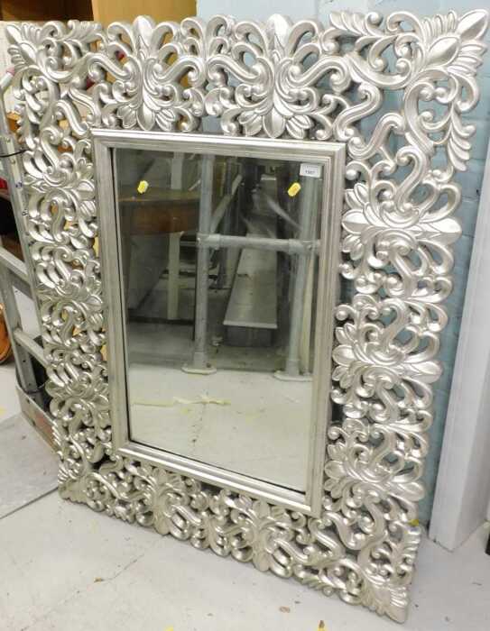 A large elaborate mirror, in silver, with pierced scroll border.