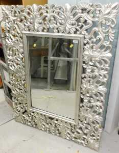 A large elaborate mirror, in silver, with pierced scroll border.