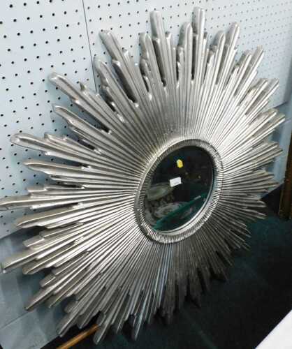 A large starburst mirror, with circular glass and silver coloured frame.