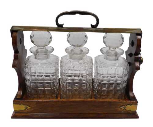 An early 20thC oak tantalus, with three cut glass bottles, and plated mounts, with lockable side,...