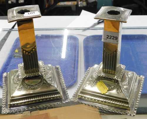 A pair of 20thC silver plated candlesticks, with square column tops on stepped bases, raised...