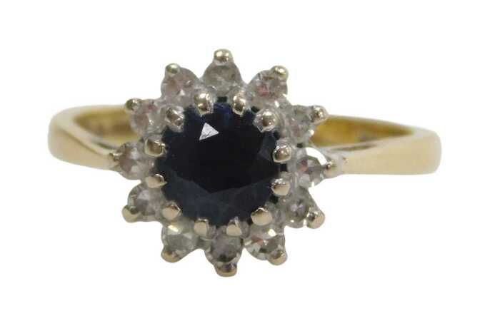 An 18ct gold sapphire and diamond cluster ring, the round brilliant cut sapphire surrounded by...