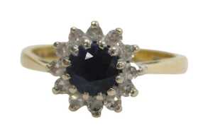 An 18ct gold sapphire and diamond cluster ring, the round brilliant cut sapphire surrounded by...