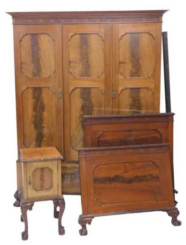 An early 20thC walnut and mahogany three piece bedroom suite, comprising triple door wardrobe...