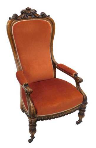A heavily carved Victorian oak showframe armchair, with scroll and floral top raised above a...