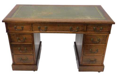An early 20thC oak twin pedestal writing desk, the one piece tooled leather top raised above...