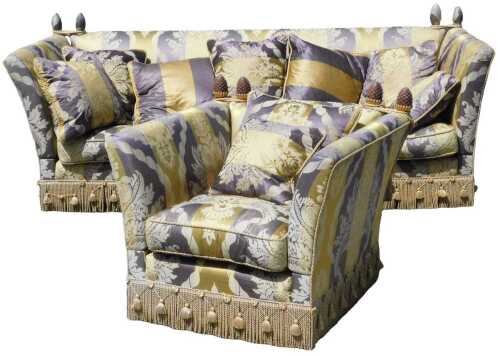 A two piece lounge suite, comprising a large knole three seater settee, probably Harrods, the sides attached to the mitre shaped finials by ropes, in a floral stripe purple and yellow material, with tassels to the base, with additional feather cushions, 1