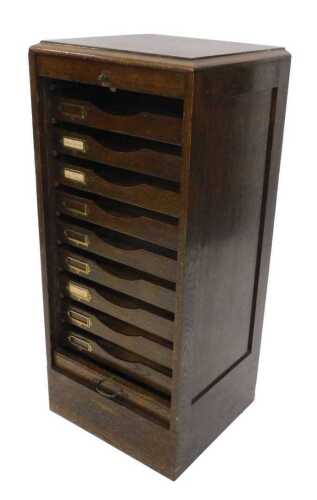 An early 20thC narrow oak tambour fronted filing cabinet, set with an arrangement of pull out...