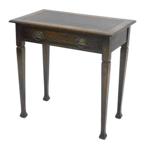 An Edwardian oak side table, the one piece tooled leather top, raised above a frieze drawer with...