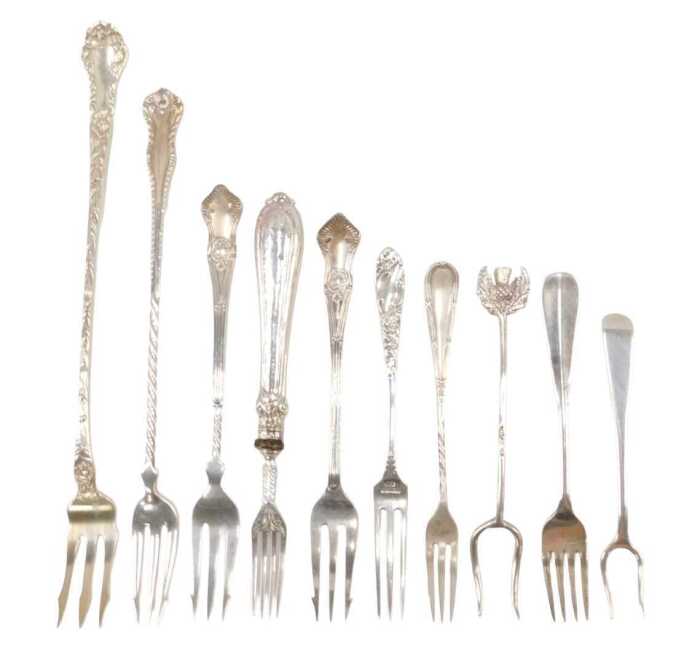 Ten various silver pickle and serving forks, to include a three pronged example with raised...