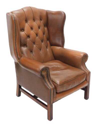 A late 20thC George III style brown leather wingback armchair, overstuffed in studded brown...