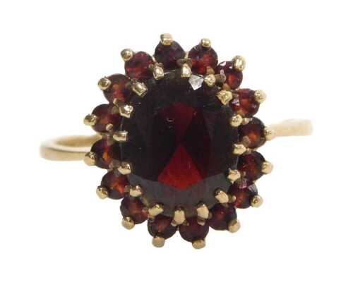 A 9ct gold garnet cluster ring, with a central oval cut garnet in raised claw setting,...