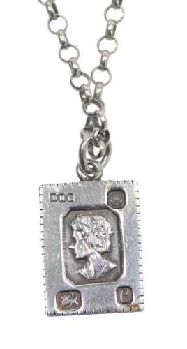 A silver pendant and chain, formed as a postage stamp, with Queen Elizabeth face, 2.5cm high, on...