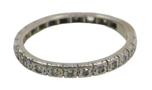 An eternity band, set with white stones, each in claw setting, on a white metal band, unmarked,...
