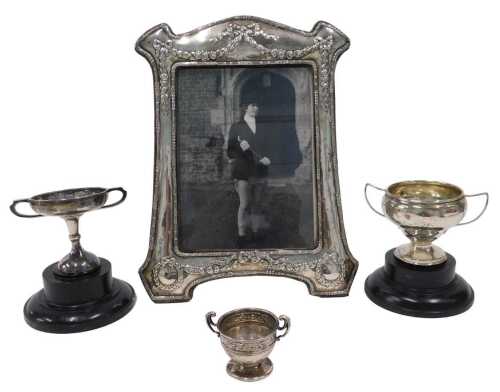 An Edward VII silver photo frame, of shaped form, with raised bellflower, ribbon and garland...
