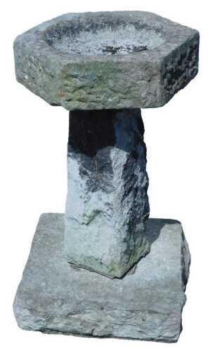 A stone bird bath of font design, the octagonal top on square tapering support, terminating in a...