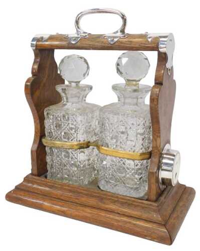 An early 20thC oak and silver mounted twin division tantalus, containing two cut glass square...