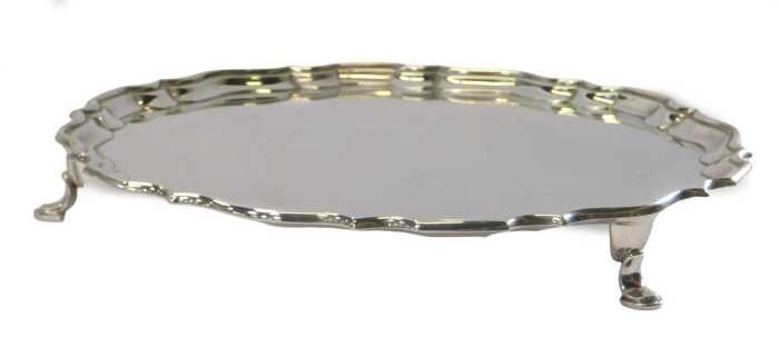A George V silver salver, of circular form with a piecrust border, raised on three hoof feet,...