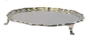 A George V silver salver, of circular form with a piecrust border, raised on three hoof feet,...